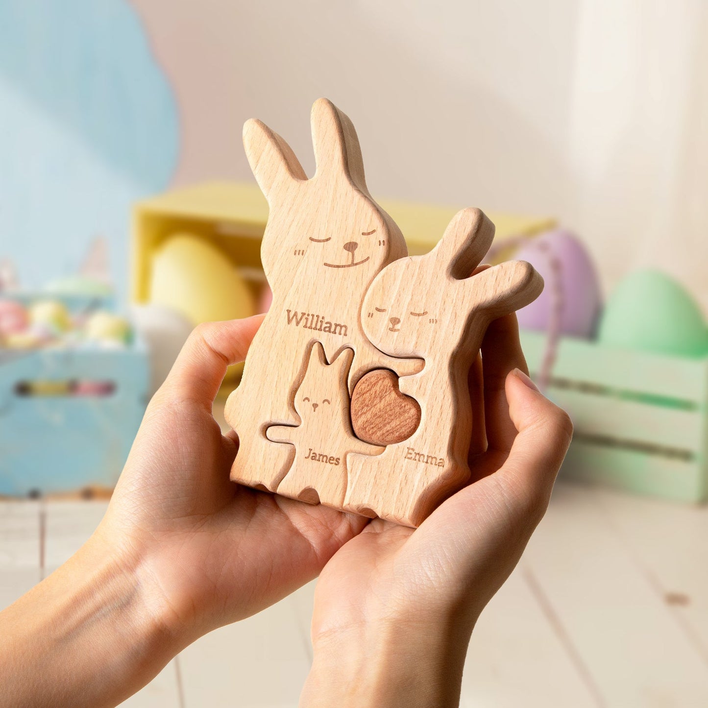 Personalized wooden rabbit family puzzle, featuring names William, Emma, and James, held in hands.