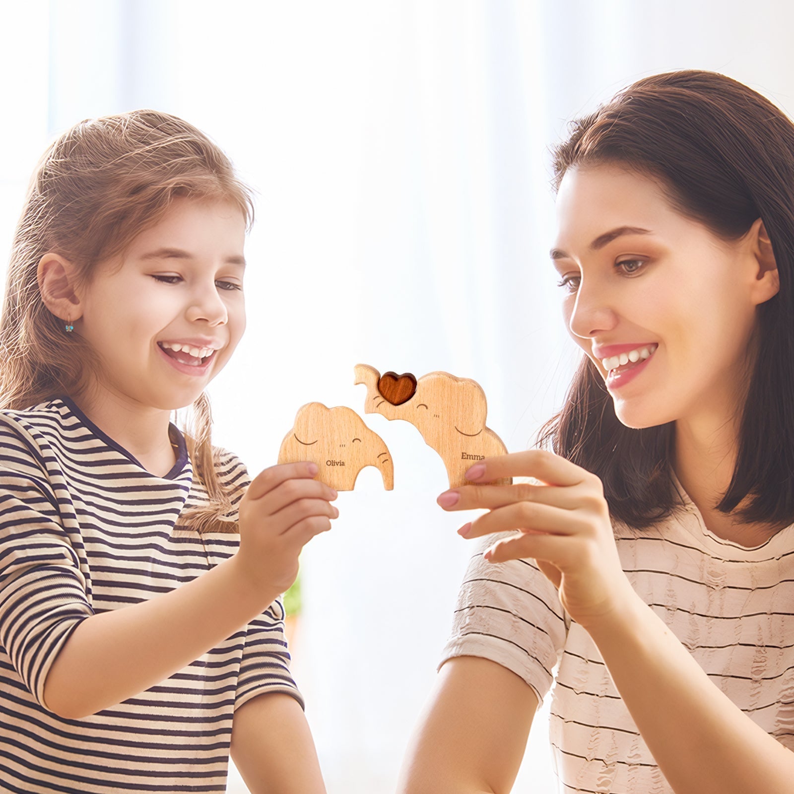 Mother and daughter joyfully holding personalized wooden elephant puzzle pieces together.